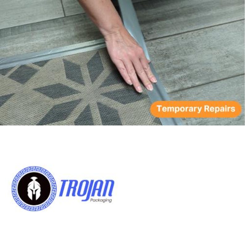 Op de afbeelding: Een zilverkleurige plakstrip aangebracht op de rand van een mat met een grijs en donkergrijs patroon. Een oranje rechthoekig label met de witte tekst Temporary Repairs is zichtbaar. Het Trojan Packaging logo bevat een zwart Spartaanse helmicoon.