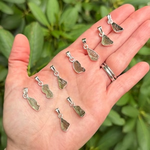 May include: Eight small, irregular, olive-green textured stone pendants, each set in a polished silver-toned metal bail. The pendants vary slightly in shape and size, displaying a rough, natural surface texture characteristic of raw mineral specimens.