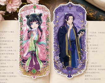 May include: Two decorative anime-style bookmarks. One features a woman in pink and green traditional clothing, the other a man in blue and purple robes. Both are framed with floral and geometric designs.