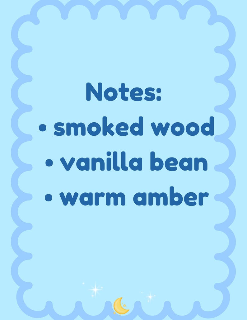 May include: A light blue card with a scalloped border displays the word "Notes:" followed by a list of scent notes: smoked wood, vanilla bean, and warm amber. A crescent moon and stars are in the bottom corner.