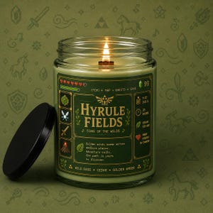 Green fantasy-inspired candle in a clear glass jar with a retro pixel adventure game style label reading Hyrule Fields. Features sage green wax, glowing wood wick flame, black lid beside the candle, and cozy green pixel background.