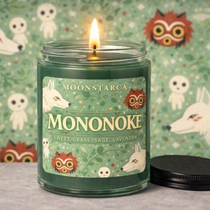 May include: A burning green candle in a glass jar, labelled "MONONOKE", with illustrations of wolves and forest spirits. The label also states the scent notes: "Sweet Grass, Sage, Lavender". The background has a repeating pattern of the same illustrations.
