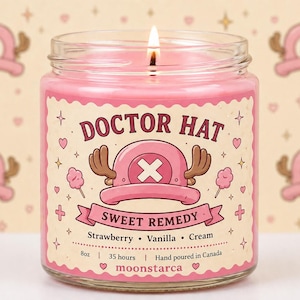 Op de afbeelding: Een brandende roze kaars in een glazen pot met een label met de tekst "DOCTOR HAT SWEET REMEDY". Het label heeft een cartoon hoed ontwerp en de woorden "Aardbei, Vanille, Room".