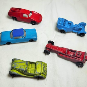 May include: Five toy cars in various colors, including red, blue, and green. The cars are made of metal and have plastic wheels. The cars are all different styles, including a sports car, a sedan, and a race car.