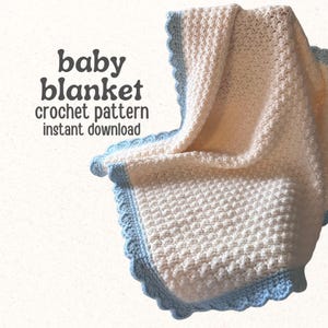 Op de afbeelding: Een witte gehaakte babydeken met een gestructureerd steekpatroon en een lichtblauwe geschulpte rand. De tekst op de afbeelding luidt: baby blanket crochet pattern instant download. De deken is gevouwen om de textuur en de randdetails te tonen.