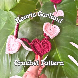 May include: A crochet garland featuring alternating light pink and dark red heart-shaped motifs connected by a yarn strand. The text "Hearts Garland" and "Crochet Pattern" is overlaid on the image in a white font with a dark outline.