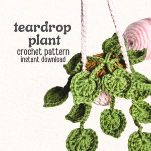 Puede incluir: Una planta en forma de lágrima tejida a ganchillo con hojas verdes y una maceta rosa claro, suspendida por correas de hilo rosa claro. El texto dice: teardrop plant crochet pattern instant download. Un ovillo de hilo rosa es visible.