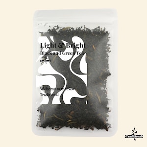 Puede incluir: Bolsa transparente llena de té negro y verde a granel. La etiqueta blanca dice "Light & Bright Black and Green Tea" y "Welcome to the New Traditional". Las hojas de té son de color verde oscuro y marrón.