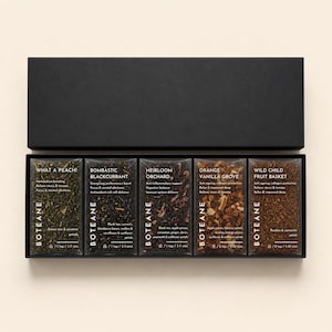 May include: A black gift box containing five tea blends in individual packets. The packets are labeled "What a Peach!", "Bombastic Blackcurrant", "Heirloom Orchard", "Orange Vanilla Grove", and "Wild Child Fruit Basket". Each packet has the brand name "BOTEANE".