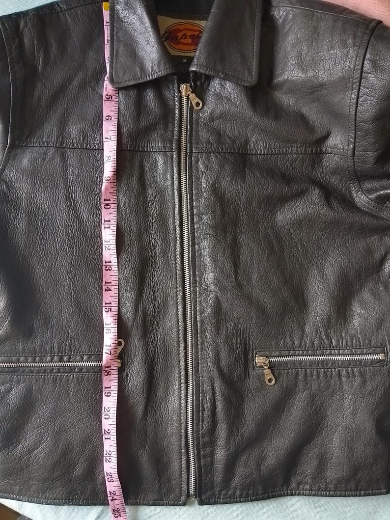 Pu&ograve; includere: Giacca in pelle nera con chiusura a zip e due tasche anteriori. La giacca &egrave; lunga circa 61 cm, misurata dalla parte superiore del colletto all'orlo inferiore. La giacca ha un collo.