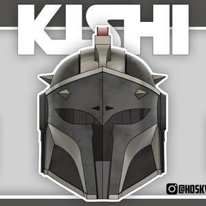 May include: A sticker featuring a stylized illustration of a Mandalorian helmet. The helmet is primarily grey with silver accents and sharp, angular details. The word "KISHI" is displayed in large white letters above the helmet.
