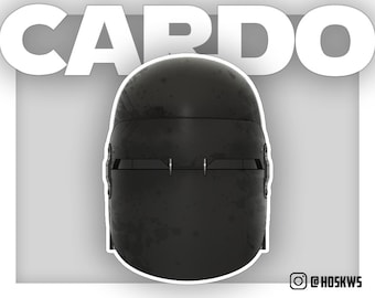May include: A black helmet with a visor and a worn, textured surface. The helmet has a raised, rectangular section on the front with a small, rectangular opening in the center. The helmet is labeled "CARDO" in white text.