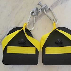 May include: Two black and yellow exercise straps with metal clips. The straps are designed to be attached to a pull-up bar or other exercise equipment.