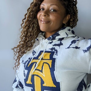 May include: White tie-dye hoodie with a large gold and navy blue "AT" patch on the front.
