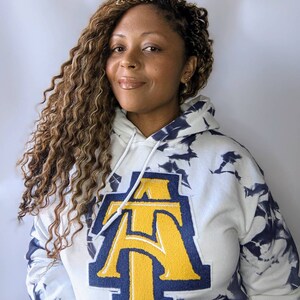 May include: White tie-dye hoodie with a large navy blue and gold embroidered letter "A" on the front.