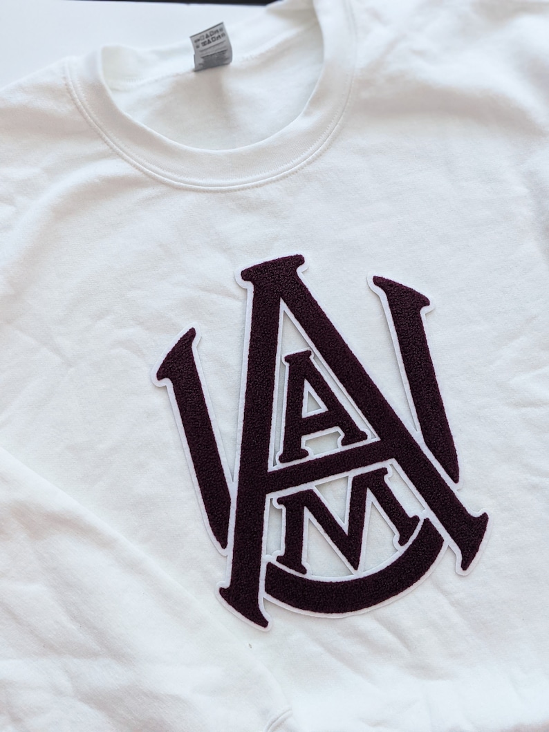 May include: White sweatshirt with a maroon felt patch of the letters "A&M" in a vintage collegiate style.