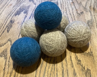 May include: Six wool dryer balls, three are blue and three are beige. The balls are arranged in a pyramid shape.