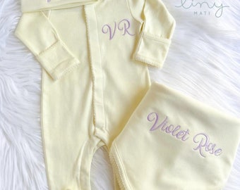 May include: A yellow baby onesie with a lavender embroidered "VR" on the front, a matching yellow hat with lavender embroidered "Violet" on the front, and a yellow burp cloth with lavender embroidered "Violet Rose" on the front.