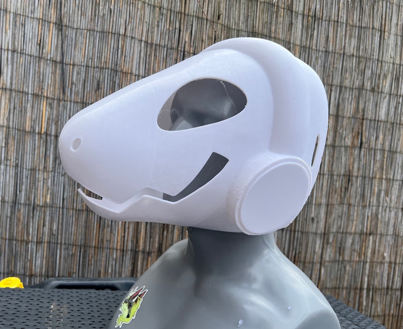 Pu&ograve; includere: Maschera in plastica bianca con un design arrotondato e futuristico. La maschera ha una grande apertura circolare sul lato e una pi&ugrave; piccola apertura sul davanti.