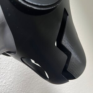 Pu&ograve; includere: Maschera facciale nera stampata in 3D con un design a zig zag e due piccoli fori laterali.