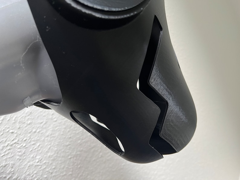 Pu&ograve; includere: Maschera facciale nera stampata in 3D con un design a zig zag e due piccoli fori laterali.