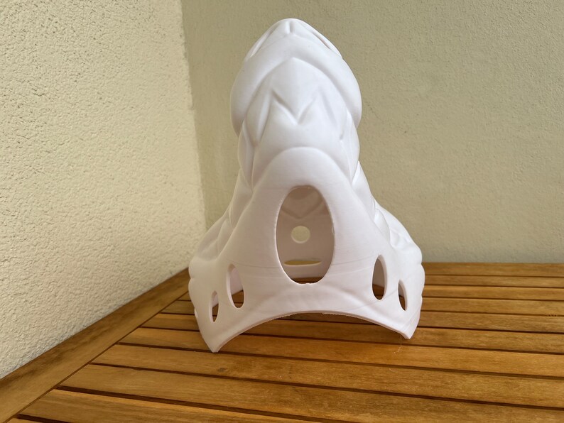Op de afbeelding: Witte plastic masker met een textuur, schubben ontwerp. Het masker heeft een grote opening voor het gezicht en verschillende kleinere gaten rond de randen.