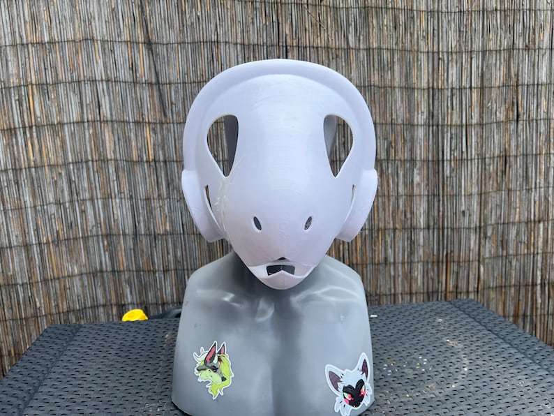 Pu&ograve; includere: Maschera in gesso bianco non verniciata con due grandi fori per gli occhi e un foro pi&ugrave; piccolo per la bocca. La maschera &egrave; su una testa di manichino grigia.