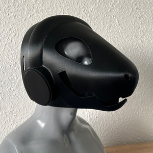 Pu&ograve; includere: Una maschera nera stampata in 3D con un design futuristico. La maschera ha un grande pezzo di testa arrotondato con un piccolo muso appuntito. La maschera ha un grande foro circolare per gli occhi su ciascun lato.