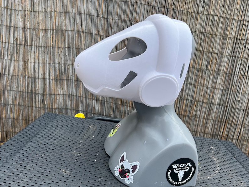 Pu&ograve; includere: Maschera di pelliccia bianca con un grande orecchio rotondo bianco sul lato. La maschera &egrave; su un manichino grigio con un adesivo bianco e nero di un teschio con il testo "W.O.A.  ESTD. 2020 THANKS FOR YOUR SUPPORT" sul davanti.