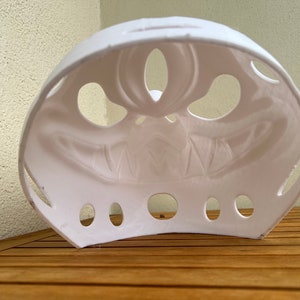 Op de afbeelding: Wit plastic Halloween-masker met een eng gezichtontwerp. Het masker heeft verschillende gaten rond de ogen en mond.