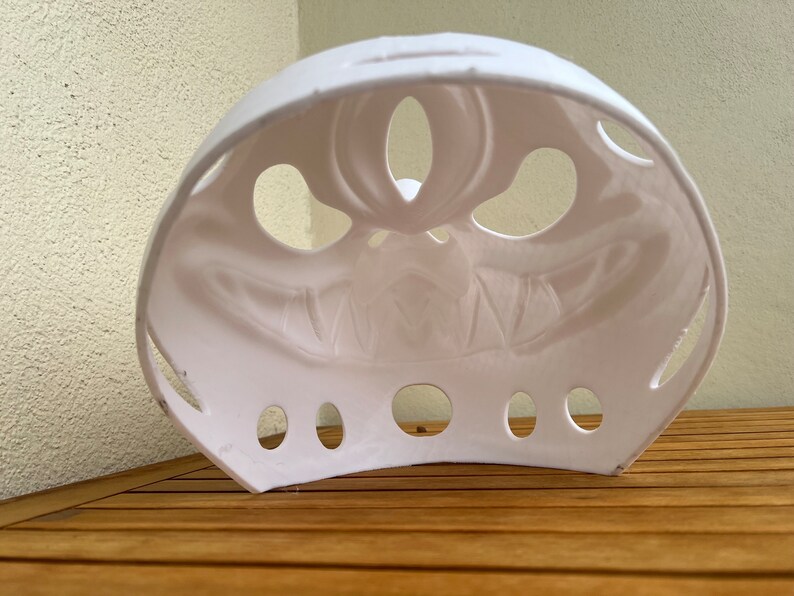 Op de afbeelding: Wit plastic Halloween-masker met een eng gezichtontwerp. Het masker heeft verschillende gaten rond de ogen en mond.