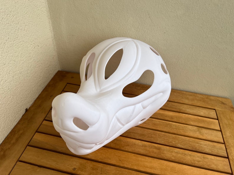 Op de afbeelding: Witte, ongeverfde vachtdiermasker met grote ooggaten en een gedetailleerde snuit.