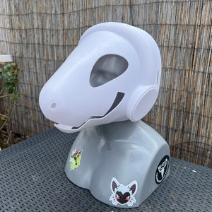 Pu&ograve; includere: Maschera di animale bianca stampata in 3D con una grande testa rotonda e un lungo muso. La maschera &egrave; su una testa di manichino grigia con adesivi.