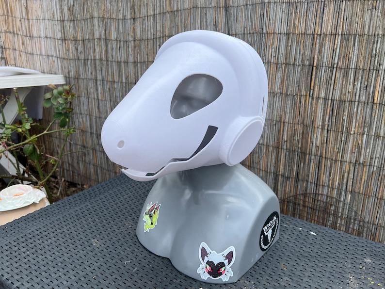 Pu&ograve; includere: Maschera di animale bianca stampata in 3D con una grande testa rotonda e un lungo muso. La maschera &egrave; su una testa di manichino grigia con adesivi.