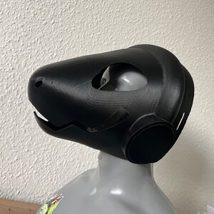 Pu&ograve; includere: Una maschera nera stampata in 3D con una grande bocca aperta e due fori per gli occhi. La maschera &egrave; progettata per assomigliare alla testa di una creatura.