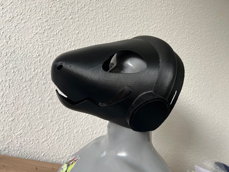 Pu&ograve; includere: Una maschera nera stampata in 3D con una grande bocca aperta e due fori per gli occhi. La maschera &egrave; progettata per assomigliare alla testa di una creatura.