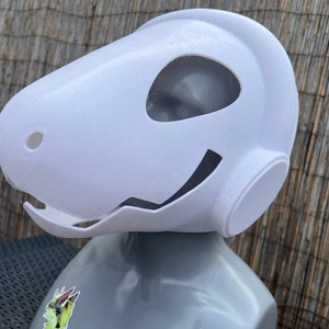 Pu&ograve; includere: Maschera di plastica bianca con un grande foro per gli occhi e un foro pi&ugrave; piccolo sul lato. La maschera ha una forma arrotondata e un leggero sorriso.