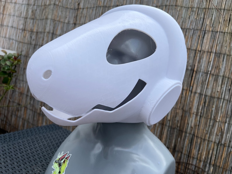 Pu&ograve; includere: Maschera di plastica bianca con un grande foro per gli occhi e un foro pi&ugrave; piccolo sul lato. La maschera ha una forma arrotondata e un leggero sorriso.