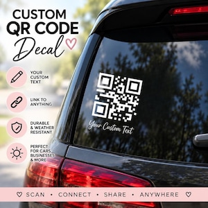 Könnte beinhalten: Ein weißer, individuell gestalteter QR-Code-Aufkleber auf der Heckscheibe eines Fahrzeugs. Das Design zeigt einen quadratischen QR-Code mit dem Text Your Custom Text in Schreibschrift darunter. Der Aufkleber befindet sich auf einer dunklen Scheibe.
