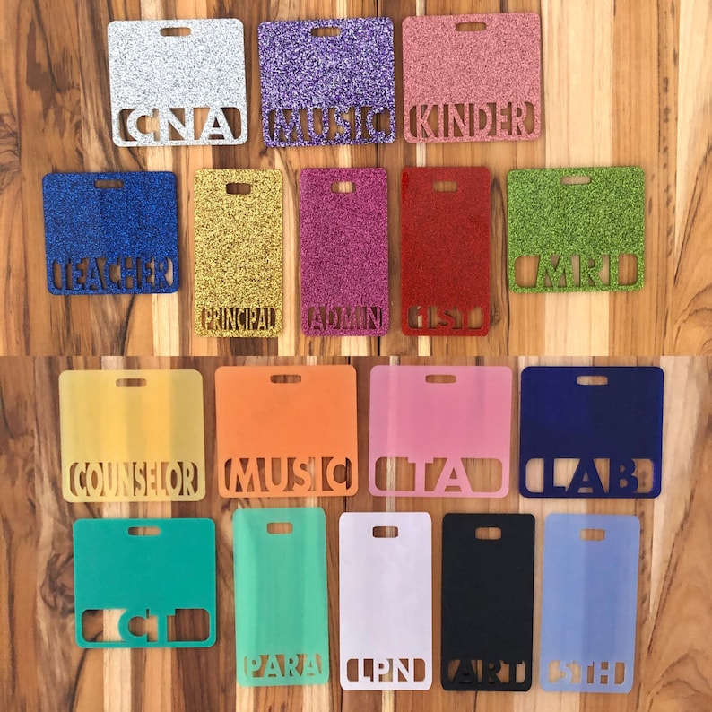 May include: A set of 15 colorful glitter name tags with various job titles, including "Teacher", "CNA", "Music", "Kinder", "Principal", "Admin", "GSL", "CMRD", "Counselor", "Music", "ITA", "LAB", "CI", "PARA", "LPND", "ART", and "CTED".