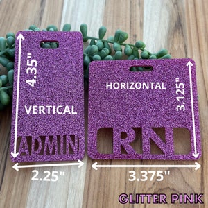 May include: Two pink glitter name tags with a hole for a lanyard. The left tag is 4.35 inches tall and 2.25 inches wide and says "ADMIN" in white letters. The right tag is 3.125 inches tall and 3.375 inches wide and says "RN" in white letters. Both tags have the words "HORIZONTAL" and "VERTICAL" printed on them.