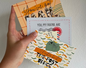 Könnte beinhalten: Drei Grußkarten mit verschiedenen Designs und Texten. Die oberste Karte ist pfirsichfarben mit den Worten "You've got" in Schreibschrift. Die mittlere Karte ist weiß mit den Worten "YOU, MY FRIEND, ARE". Auf der unteren Karte steht "I'd rather be at THE POST OFFICE".