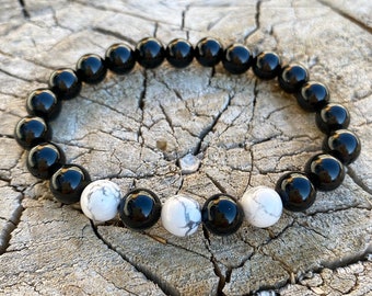 May include: A black and white beaded bracelet with alternating black and white beads. The bracelet is made of natural stones and is approximately 7 inches in length.
