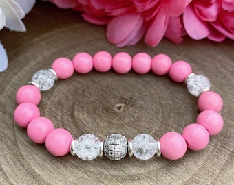 Puede incluir: Un brazalete de cuentas de cristal rosa y transparente con un dije de plata. El brazalete está hecho con cuentas redondas y una cuenta espaciadora de plata.