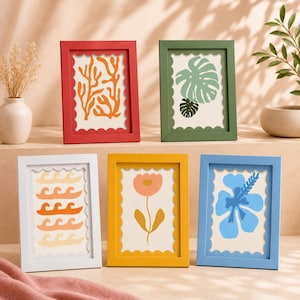 May include: Five rectangular picture frames with scalloped inner edges, each containing a unique print. The frames are red, green, white, yellow, and blue. The prints feature orange coral, green monstera leaves, orange waves, a pink flower, and a blue hibiscus.
