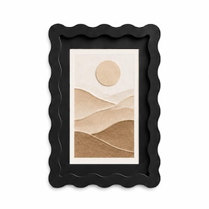 May include: A rectangular wall art piece featuring a textured landscape with rolling hills in shades of beige and brown under a circular sun, encased in a thick black frame with a wavy, scalloped outer edge and a smooth inner border.