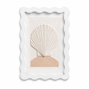 May include: A rectangular wall art piece featuring a white scalloped frame. The center displays a raised, textured white seashell relief positioned above a semi-circular, textured light peach-colored base on a cream-colored background.