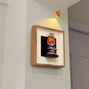 May include: A wall-mounted shelf with a figurine of a young person reading, wearing glasses and a stack of books. The shelf has a wooden frame with a white border. An orange lamp illuminates the shelf. The figurine is reading a book.