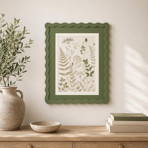 May include: A rectangular wall frame with a scalloped edge in a muted olive green finish. The frame contains a botanical print featuring various pressed ferns, wildflowers, and delicate stems in shades of green and beige on a light background.
