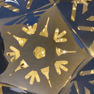 Peut inclure: Une flocon de neige en papier blanc avec des d&eacute;coupes complexes, &eacute;clair&eacute; par des lumi&egrave;res blanches chaudes. Le flocon de neige est pli&eacute; en une forme tridimensionnelle, cr&eacute;ant un design d&eacute;licat et festif. Le texte "Paper Soul" est visible dans le coin sup&eacute;rieur gauche de l'image.